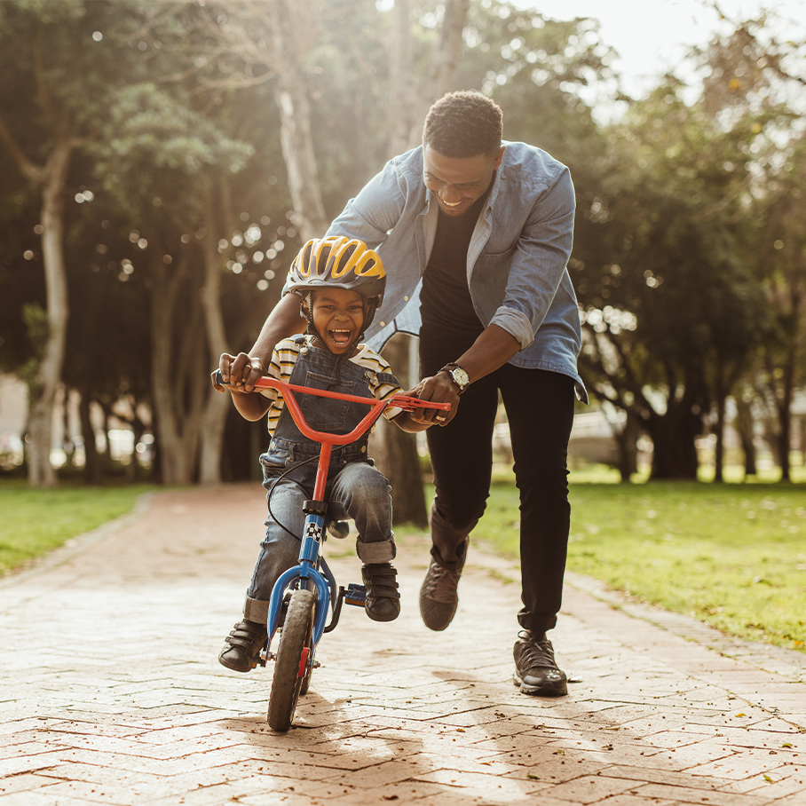 Dad helping his son ride a bike