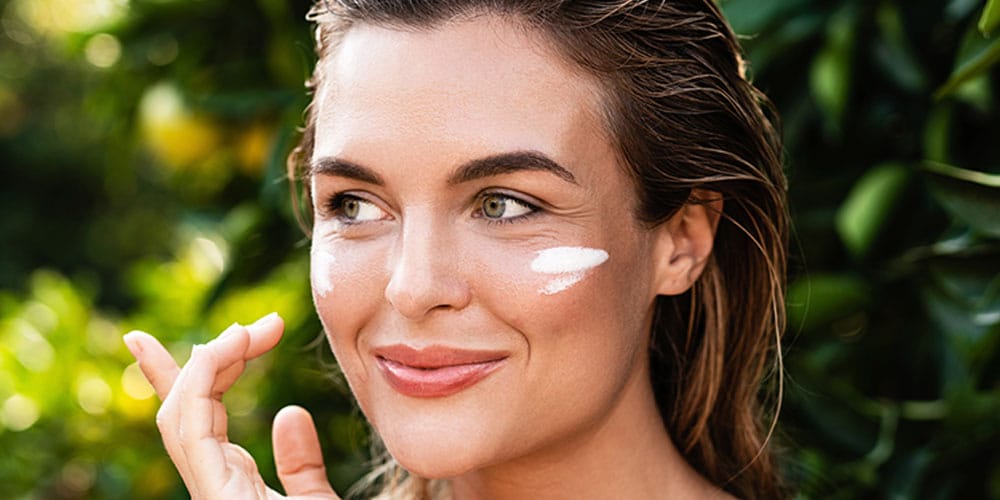 woman putting on sunscreen after getting summer Botox
